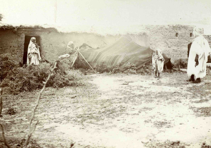 Une habitation en torchis (gourbi), une tente et ses occupants.