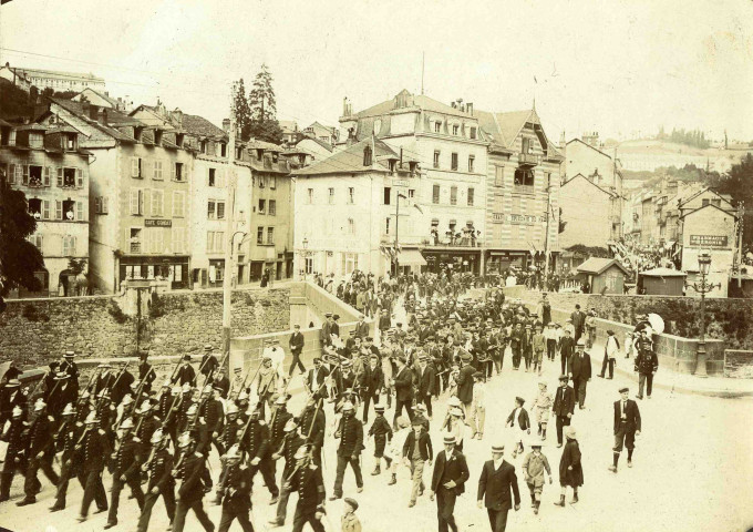 Les compagnies de sapeurs-pompiers et l'Harmonie des Enfants de Tulle traversent le pont de la Barrière.