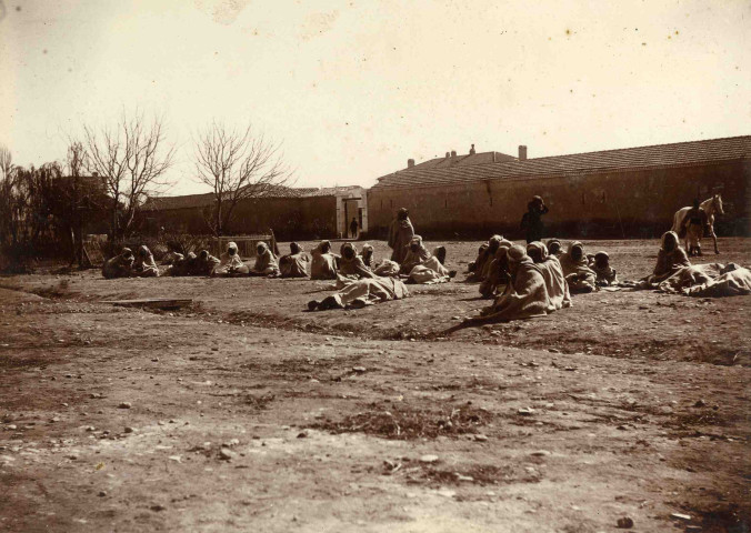 Hommes assis devant la maison du caïd.