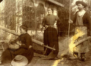 Jeune fille assise portant un panier avec à ses cotés, une femme et un homme revêtu d'un long tablier sont vraisemblablement occupés à des travaux de jardinage.