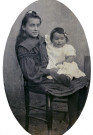Portrait de jeune fille assise sur une chaise (Marie-Lucie Montagut ?) tenant un bébé (Georgette Guinot ?).