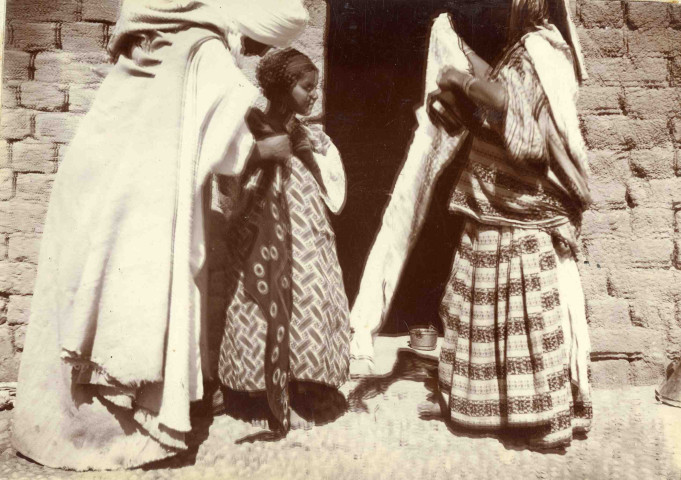 Une petite fille portant voile et tenue d'apparat, accompagnée de ses parents.