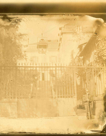 Entrée d'une bâtisse : devant le portail, un militaire monte la garde.