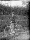 Vélocipédiste au canotier, sur un chemin.
