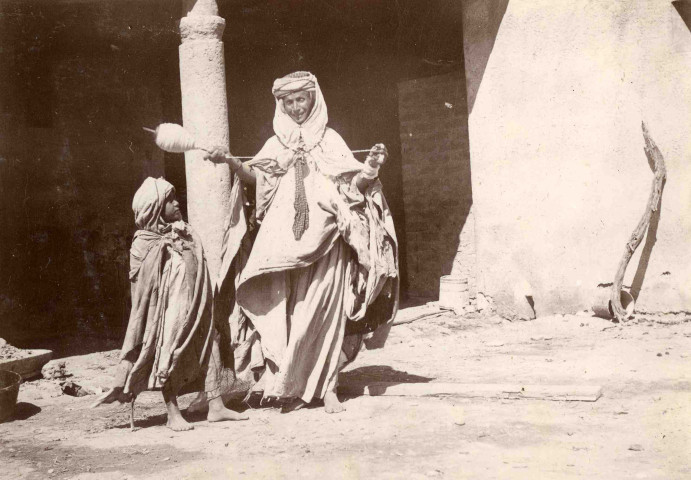 Fileuse arabe portant quenouille et un enfant.