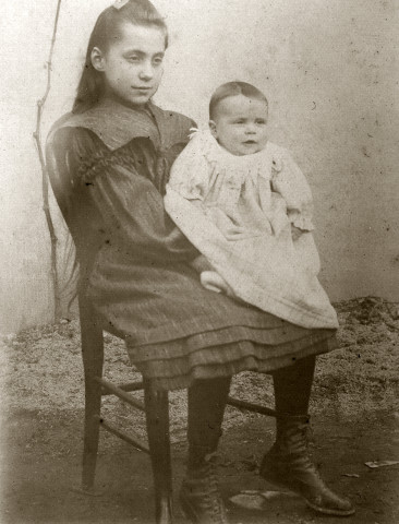 Portrait de jeune fille assise sur une chaise (Marie-Lucie Montagut ?) tenant un bébé (Albertine Guinot ?).