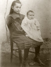 Portrait de jeune fille assise sur une chaise (Marie-Lucie Montagut ?) tenant un bébé (Albertine Guinot ?).