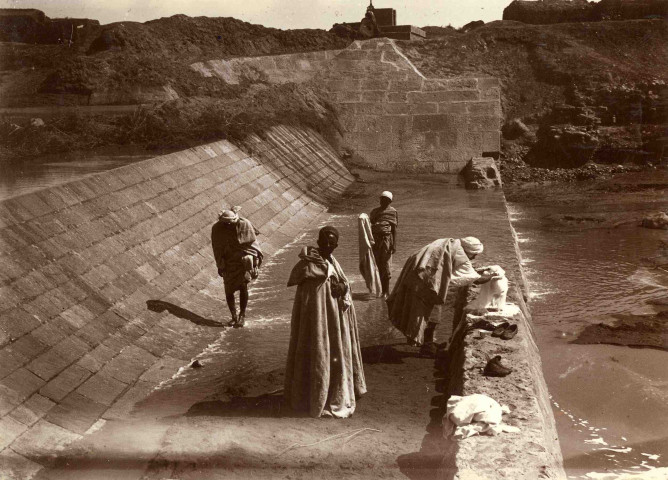 Hommes lavant des vêtements au barrage.