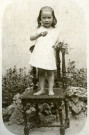 Portrait en pied d'un jeune enfant, debout sur une chaise.