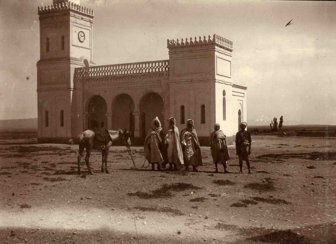 Groupe d'hommes devant une mosquée.