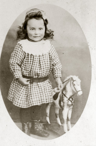 Portrait en pied d'un jeune enfant, au cheval à roulettes.