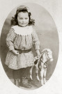 Portrait en pied d'un jeune enfant, au cheval à roulettes.