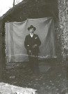 Portrait en pied d'un homme près de la remise à bois.