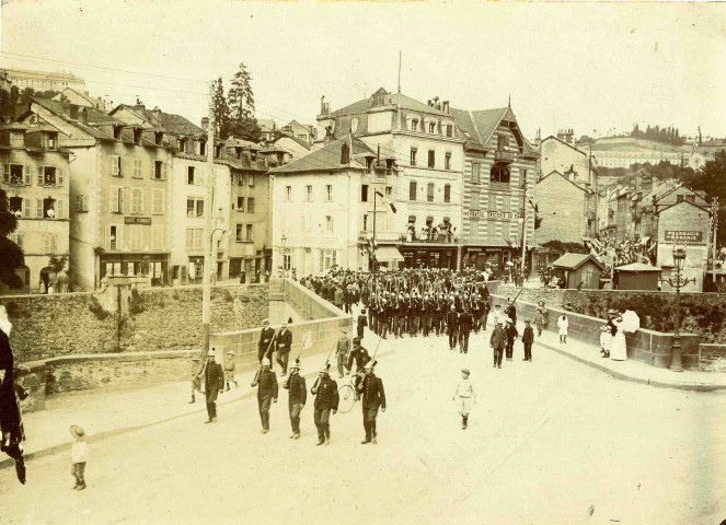 Les compagnies de sapeurs-pompiers et l'Harmonie des Enfants de Tulle traversent le pont de la Barrière.