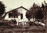 Une maison avec jardin ; un militaire jouant avec son chien.