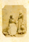Deux femmes, l'une assise, l'autre debout, en costume traditionnel.