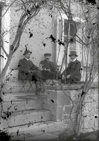 Café de la gare : trois hommes attablés en terrasse.