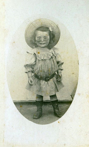 Portrait en pied d'un jeune enfant aux lunettes.