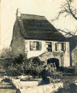 Maison de pierre à toiture en chaume, femme est assise au premier plan.