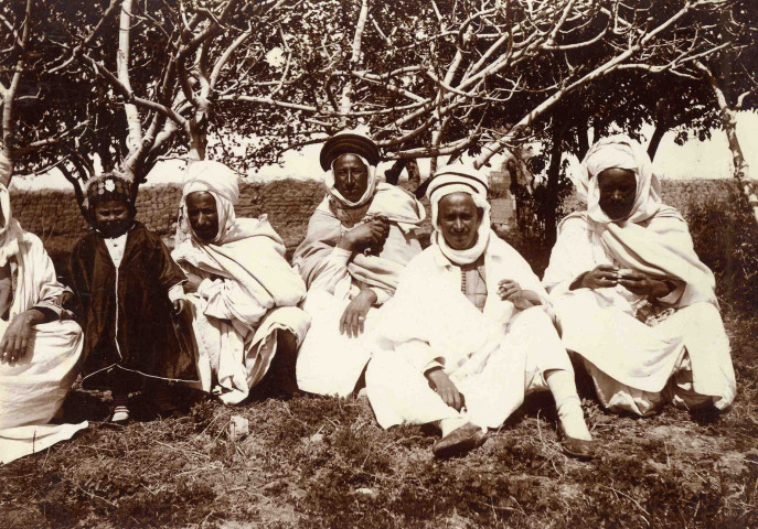 Portrait du caïd entouré d'hommes et d'un enfant dans un jardin.