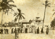 Officiers militaires et autochtones devant une grande bâtisse de type colonial.
