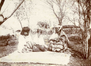 Femmes et enfant assis sur un tapis dans un jardin.