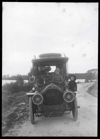 Automobile avec chauffeur, vue de face, au bord de l'étang [de Brach].
