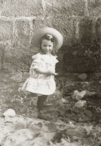 Portrait en pied d'un jeune enfant dans une cour.